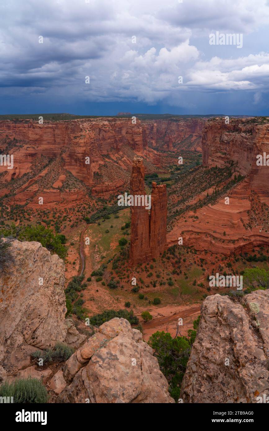 Überblick über den Canyon de Chelly mit der als Spider Rises bekannten Felsformation, die aus dem Canyon hervorgeht, im Tal, umgeben von der erodierten roten ... Stockfoto