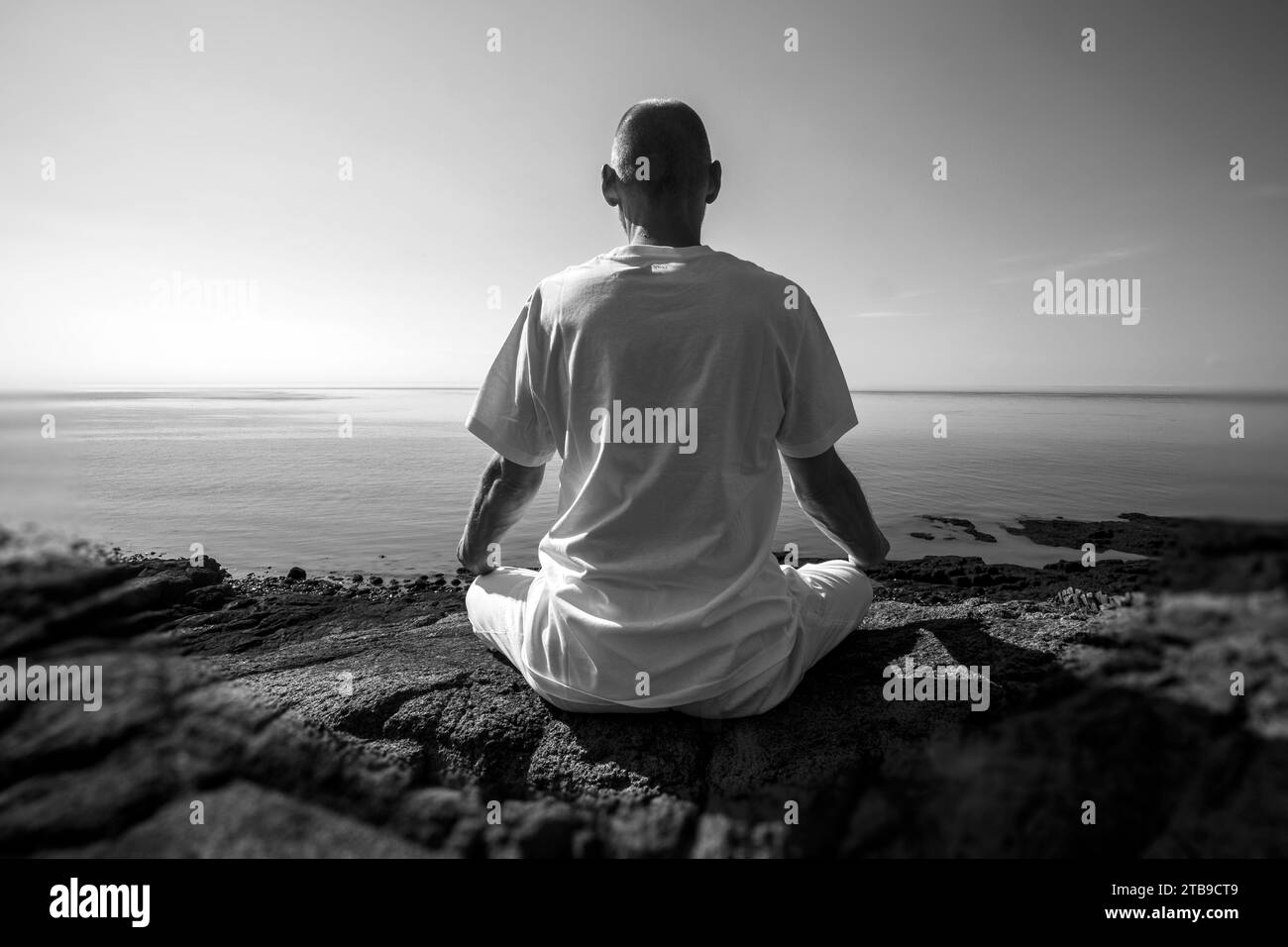 Mann, der in Lotus-Position am Atlantik meditiert; Digby, Nova Scotia, Kanada Stockfoto