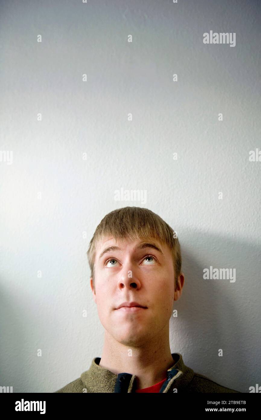 Porträt eines jungen erwachsenen Mannes, der vor weißem Hintergrund aufblickt; Fairbanks, Alaska, Vereinigte Staaten von Amerika Stockfoto