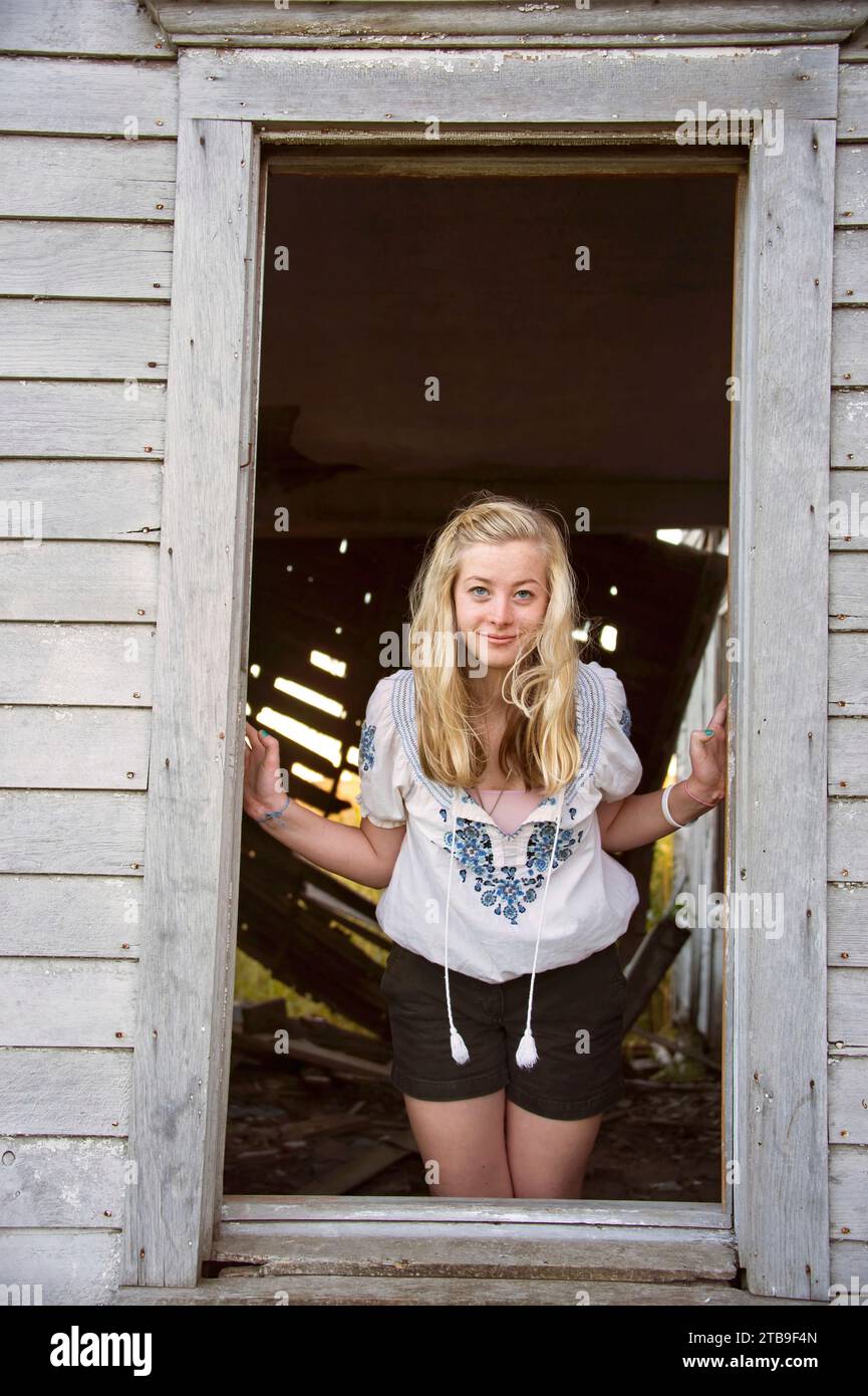 Porträt eines Teenagers, das durch das Fenster einer alten Scheune schaut; Dunbar, Nebraska, Vereinigte Staaten von Amerika Stockfoto