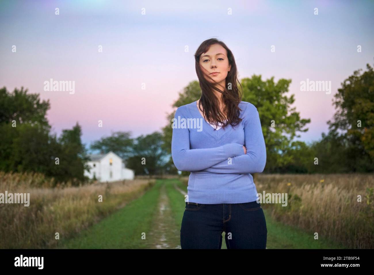 Porträt eines Jugendlichen Mädchens, das am Ende der Straße bei einem alten Bauernhaus steht; Dunbar, Nebraska, Vereinigte Staaten von Amerika Stockfoto