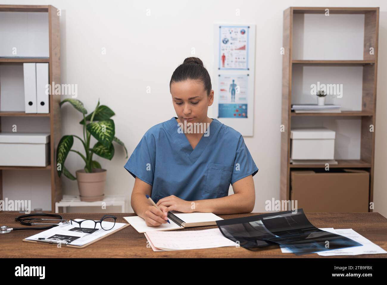 Arzt in blauer Uniform konzentriert sich auf Überprüfung medizinischer Dokumente und Testergebnisse, genaue Aufzeichnungen. Stockfoto