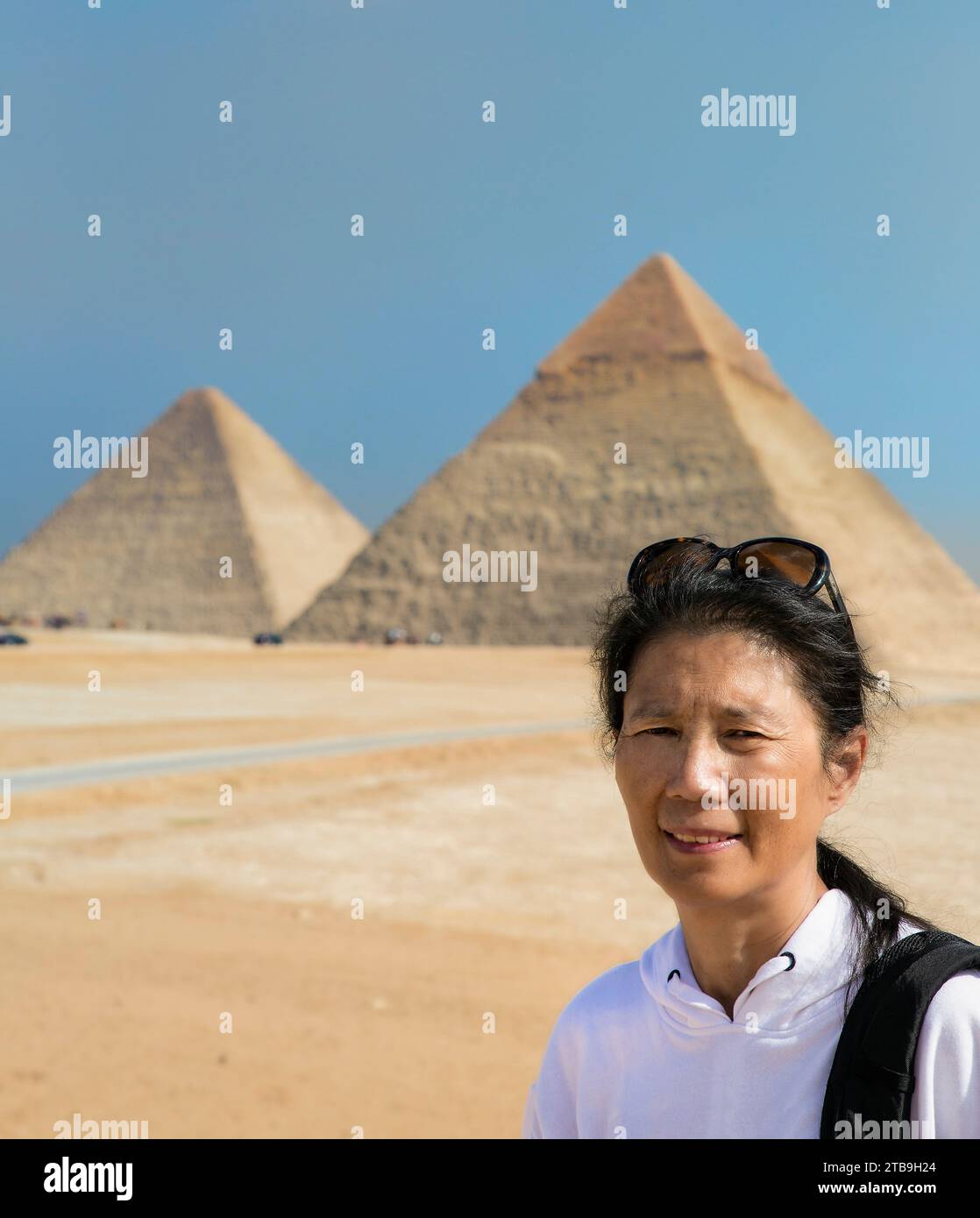 Nahaufnahme einer asiatischen Touristenfrau, die vor den Pyramiden von Gizeh steht; Gizeh, Kairo, Ägypten Stockfoto