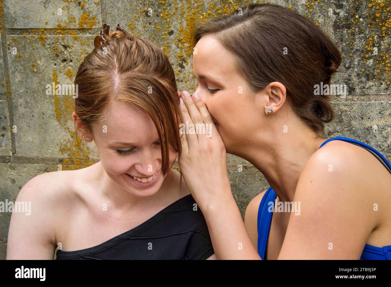 Zwei junge Frauen in Formalwear flüstern einander Geheimnisse zu; Lincoln, Nebraska, Vereinigte Staaten von Amerika Stockfoto