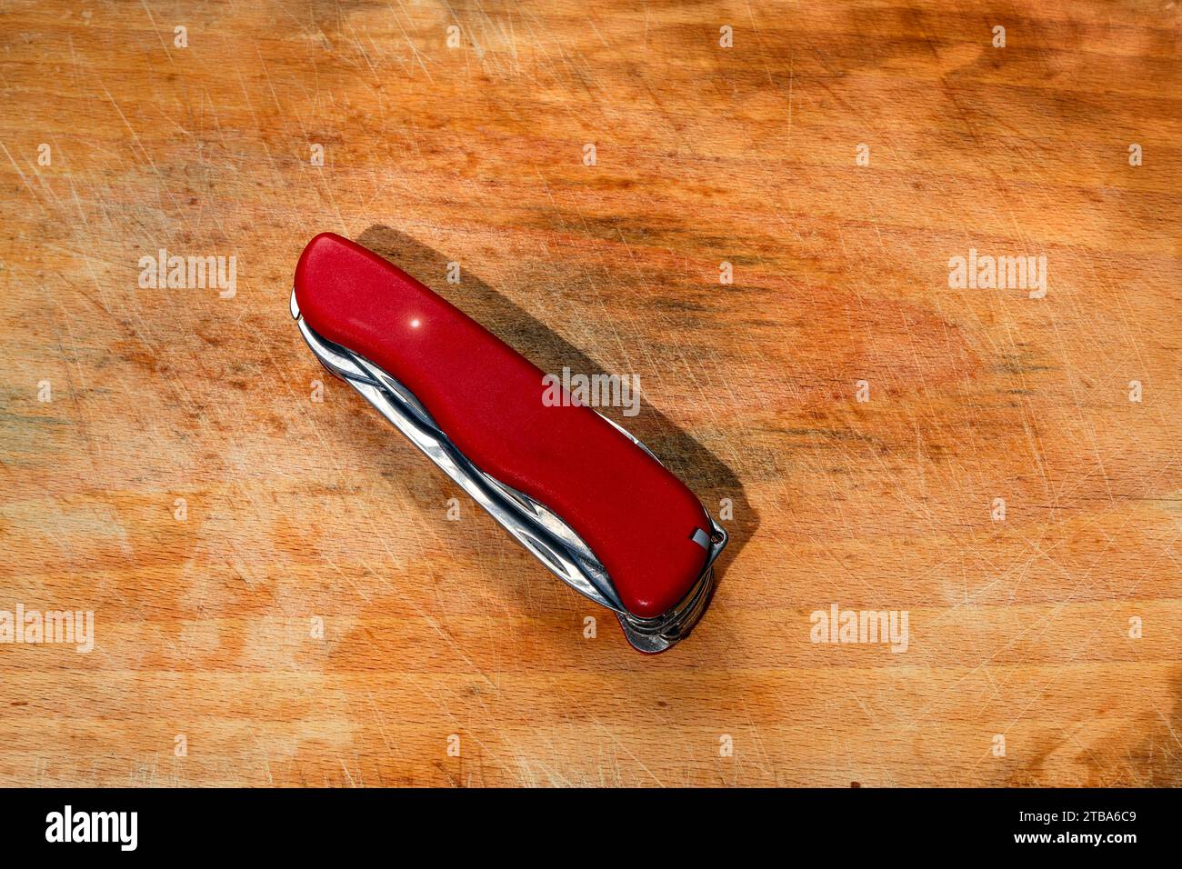 Rotes Taschenmesser und Multifunktionswerkzeug auf Holzbrett zum Schneiden von Gemüse, Obst und Fleisch Stockfoto