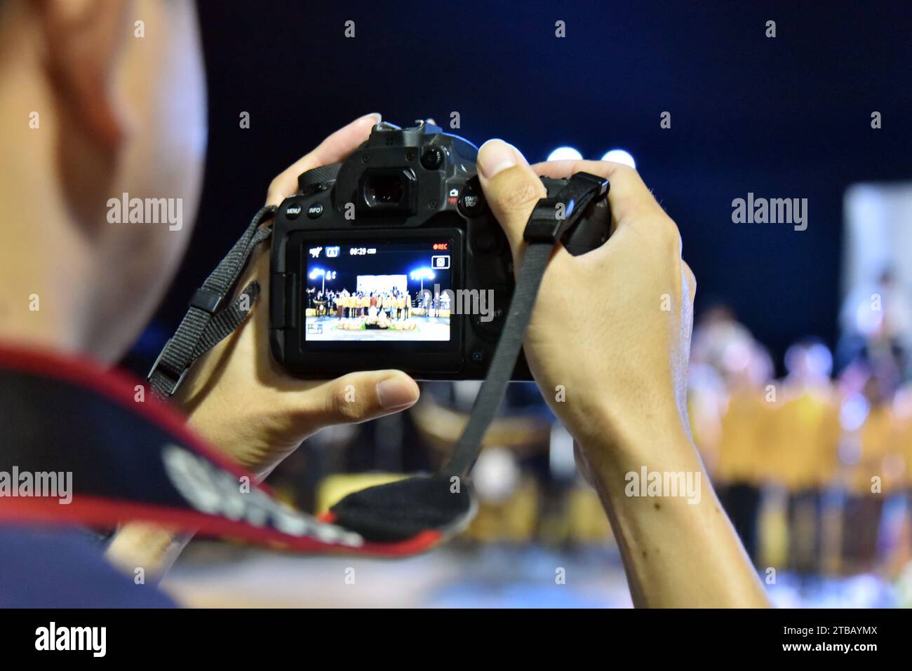 Man nutzt eine Kamera, während Jugendliche und Studenten, die örtliche Schulen und Hochschulen und Universitäten in Nakhon Phanom, Isaan, Thailand, Südostasien besuchen, in einem Konzert ihre musikalischen und tänzerischen Fähigkeiten am Abend des 5. Dezember 2023 zeigen. Der Veranstaltungsort war draußen am Fluss und es war für jeden kostenlos, bei der milden Temperatur teilzunehmen. Stockfoto