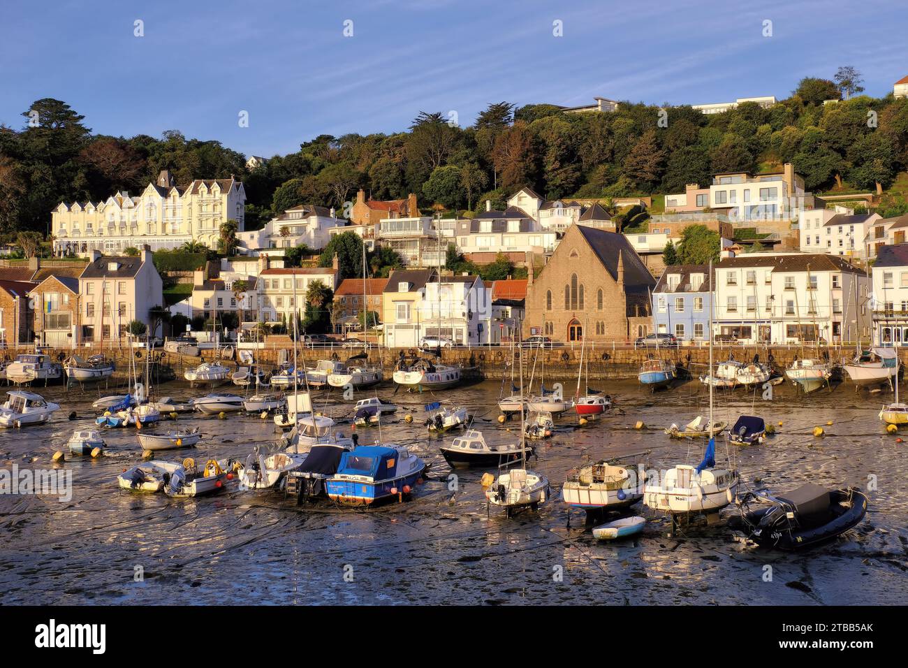 St Aubin: Yachten und Boote im Hafen mit Kirche und Somerville Hotel kurz nach Sonnenaufgang in St Aubin, Kanalinseln, Großbritannien Stockfoto