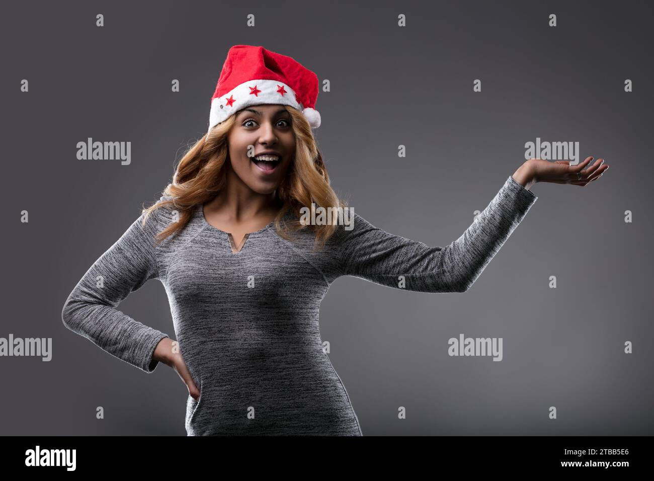 Mit einem Weihnachtsmann-Hut und einem fröhlichen Lächeln verkörpert sie die Stimmung der Saison, wie IHR PRODUKT zeigt Stockfoto