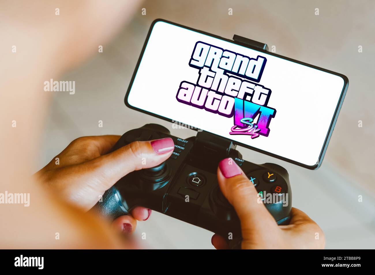 Brasilien. Dezember 2023. In dieser Fotoabbildung wird das Grand Theft Auto VI (GTA 6) Logo auf einem Smartphone-Bildschirm angezeigt, während eine Person auf einem Gaming-Gamepad spielt. Quelle: SOPA Images Limited/Alamy Live News Stockfoto