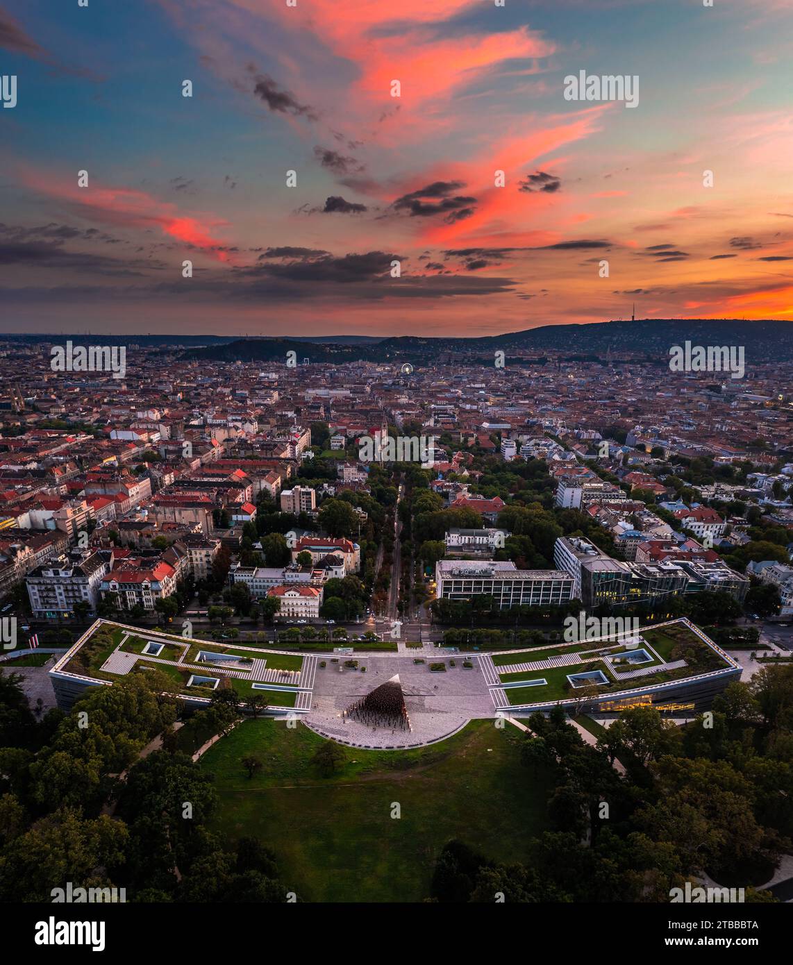 Budapest, Ungarn - Panoramablick auf das Ethnographische Museum im Stadtpark mit der Skyline von Budapest im Hintergrund und farbenfroher Sonnenuntergang Stockfoto