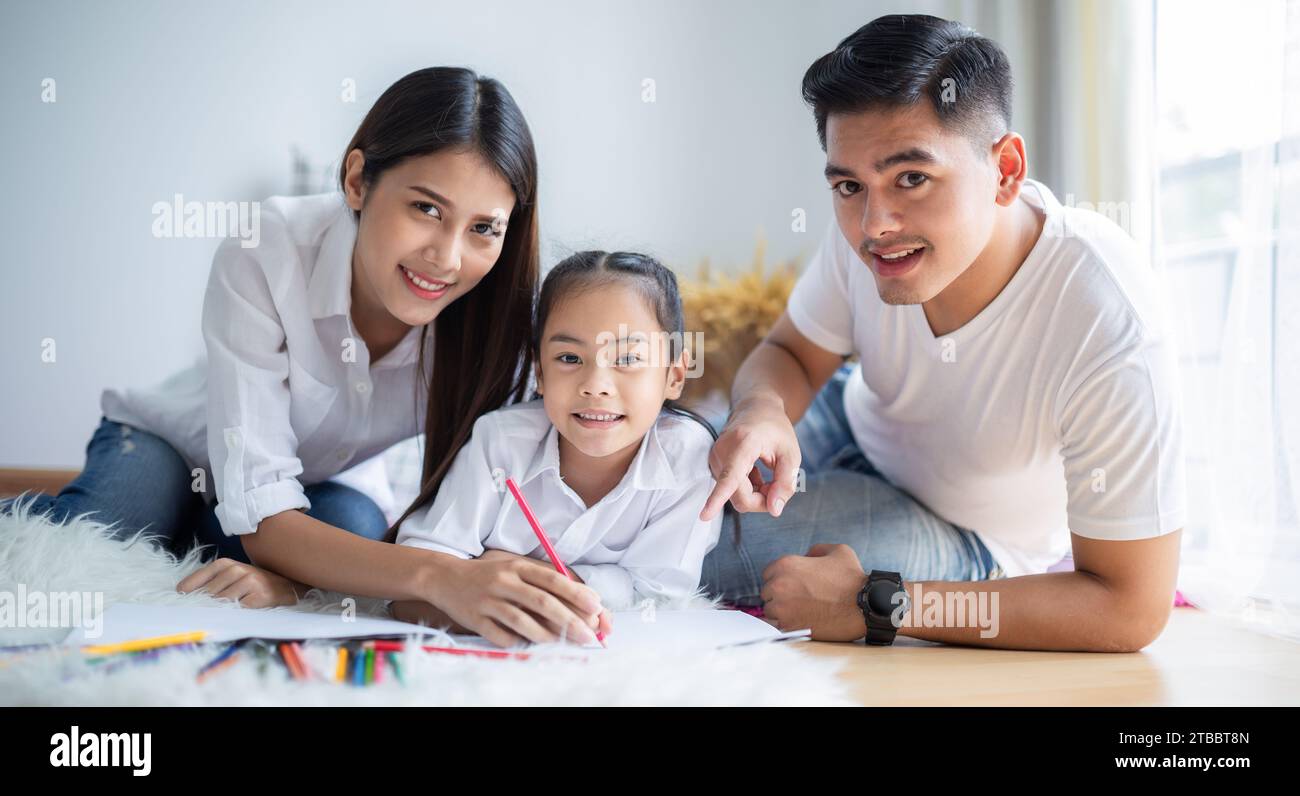 Vater und Mutter bringen ihrer Tochter das Malen bei. In der Familie herrscht Wärme. Stockfoto