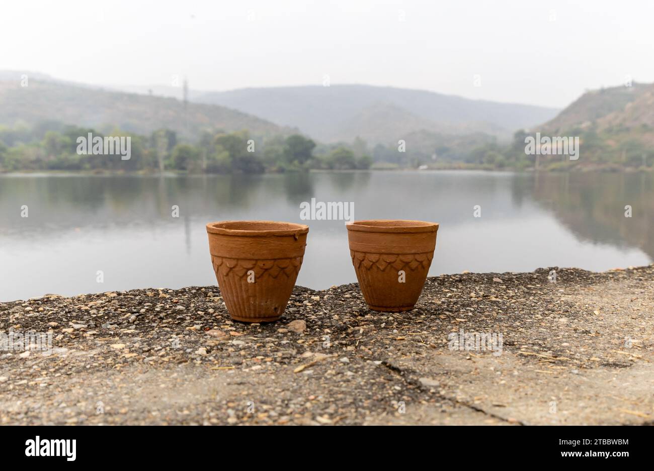 Heißer Tee serviert in traditioneller handloser Töpfertontasse mit verschwommener Bergsee-Landschaft Stockfoto
