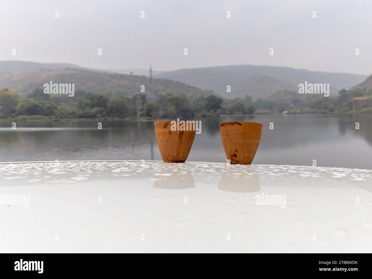 Heißer Tee serviert in traditioneller handloser Töpfertontasse mit verschwommener Bergsee-Landschaft Stockfoto