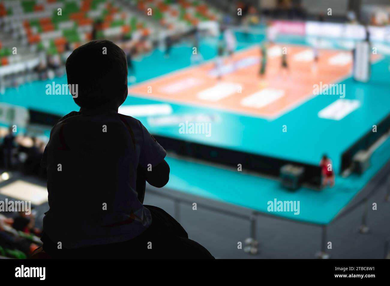 Silhouette eines kleinen Jungen Huckepack von seinem Vater und Volleyballspiel im Hintergrund Stockfoto