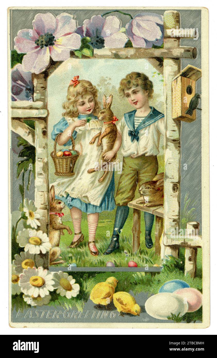 Originelle, charmante Ostergrüßkarte aus der edwardianischen Ära, Bruder und Schwester, Mädchen ist wie Alice im Wunderland gekleidet, der Junge trägt einen typischen Matrosenanzug, der zu dieser Zeit beliebt ist. Es gibt Eier in einem Korb, Küken, Hasen oder Kaninchen. blumenrand. Gesendet aus Brooklyn, USA, ca. 1905 / 1910. Stockfoto
