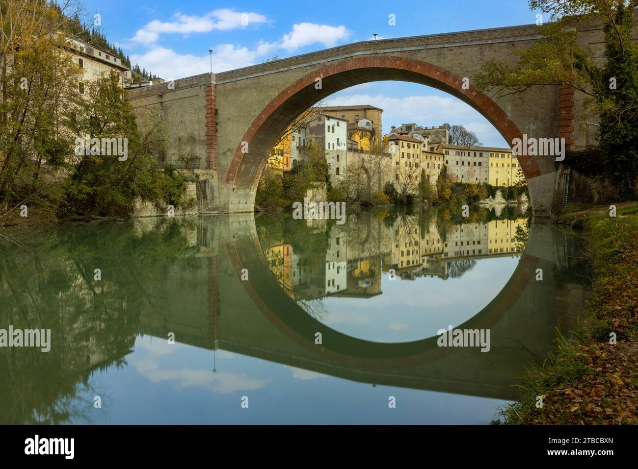 Blick auf Fossombrones charmante Altstadt vom Park aus, mit der Ponte della Concordia, die sich über den Metauro-Fluss erstreckt. Stockfoto