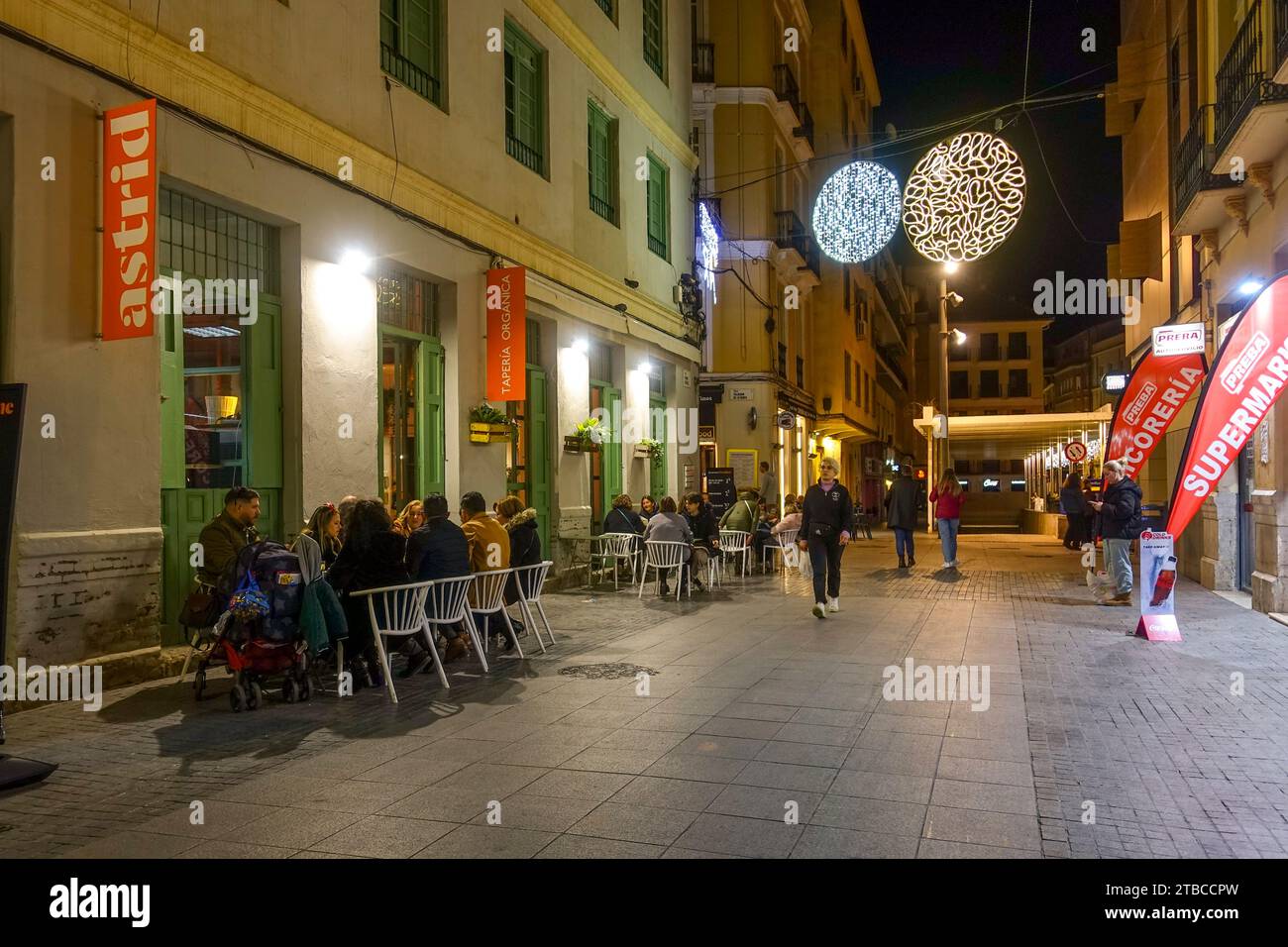Außenterrasse mit Leuten im Winter, Blick auf die Straße bei Nacht, Malaga, Andalusien, Spanien. Stockfoto