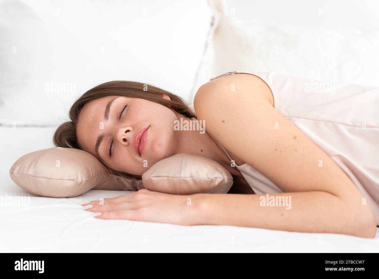 Weißes sexy Mädchen 20-25 Jahre alt in Seidenwäsche schläft auf einem Schönheitskissen auf dem Bett im Schlafzimmer Stockfoto