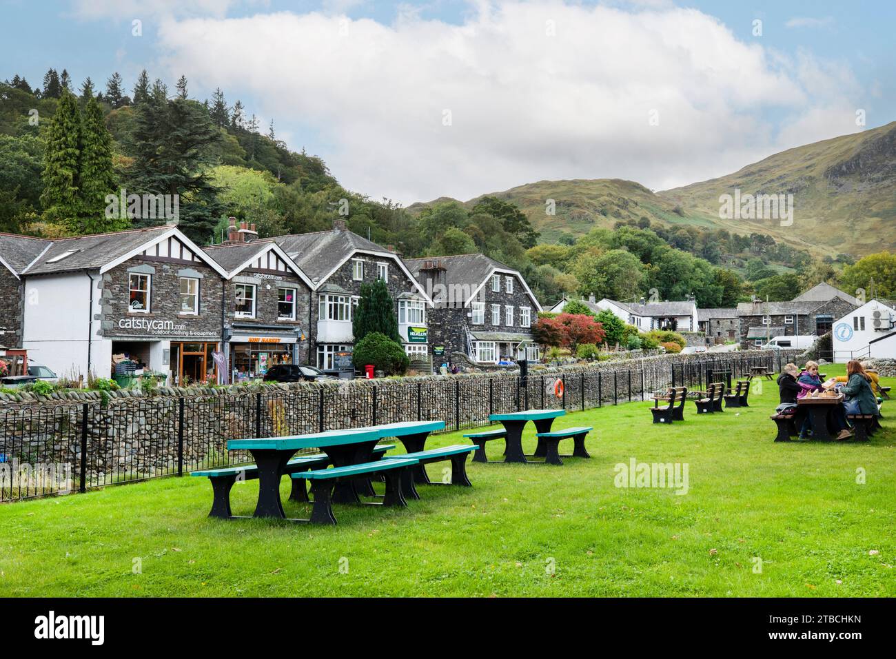 Leute sitzen am Picknicktisch neben dem Glenridding Beck River in glenridding, Lake District, Cumbria Stockfoto