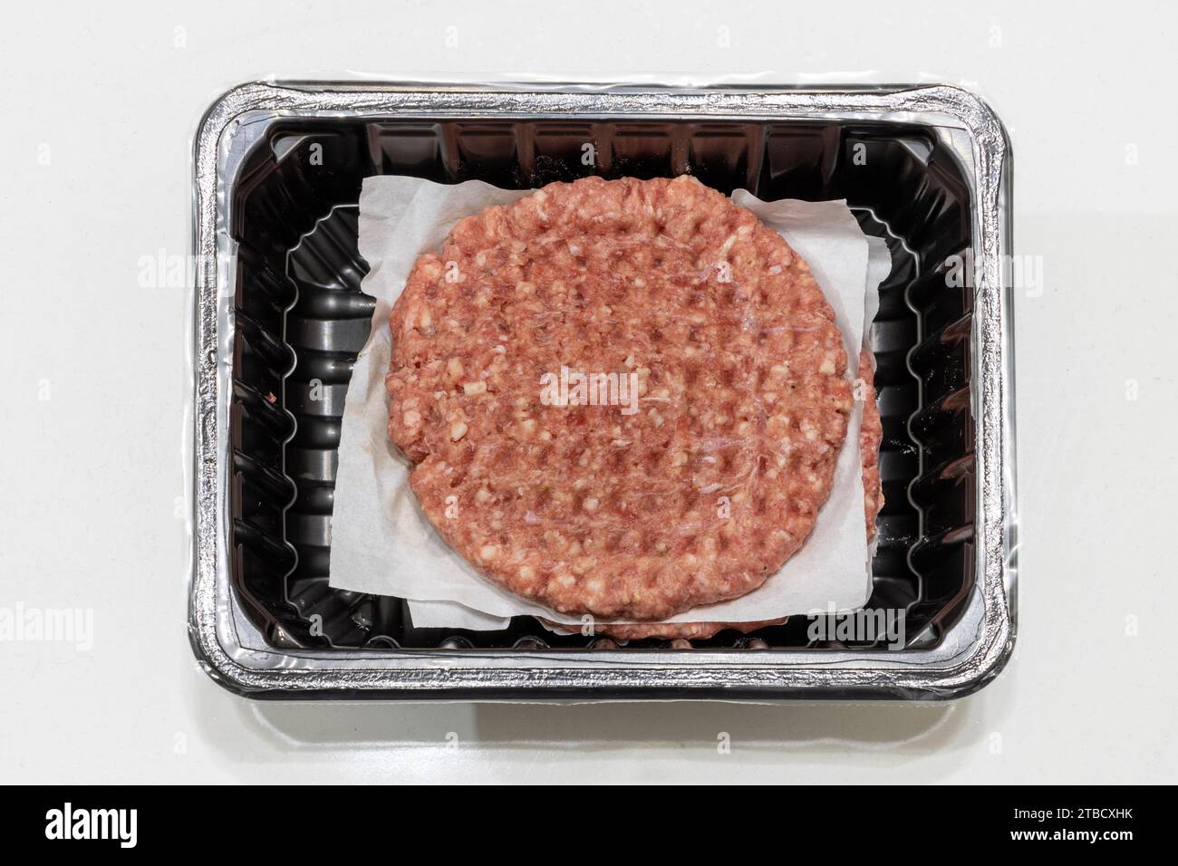 Rohe Hamburger Hackfleisch-Pastete in Plastikverpackung, verpackte Lebensmittel, Fast Food. Verkauf fertiger Lebensmittel. Isolierter weißer Hintergrund, Draufsicht Stockfoto