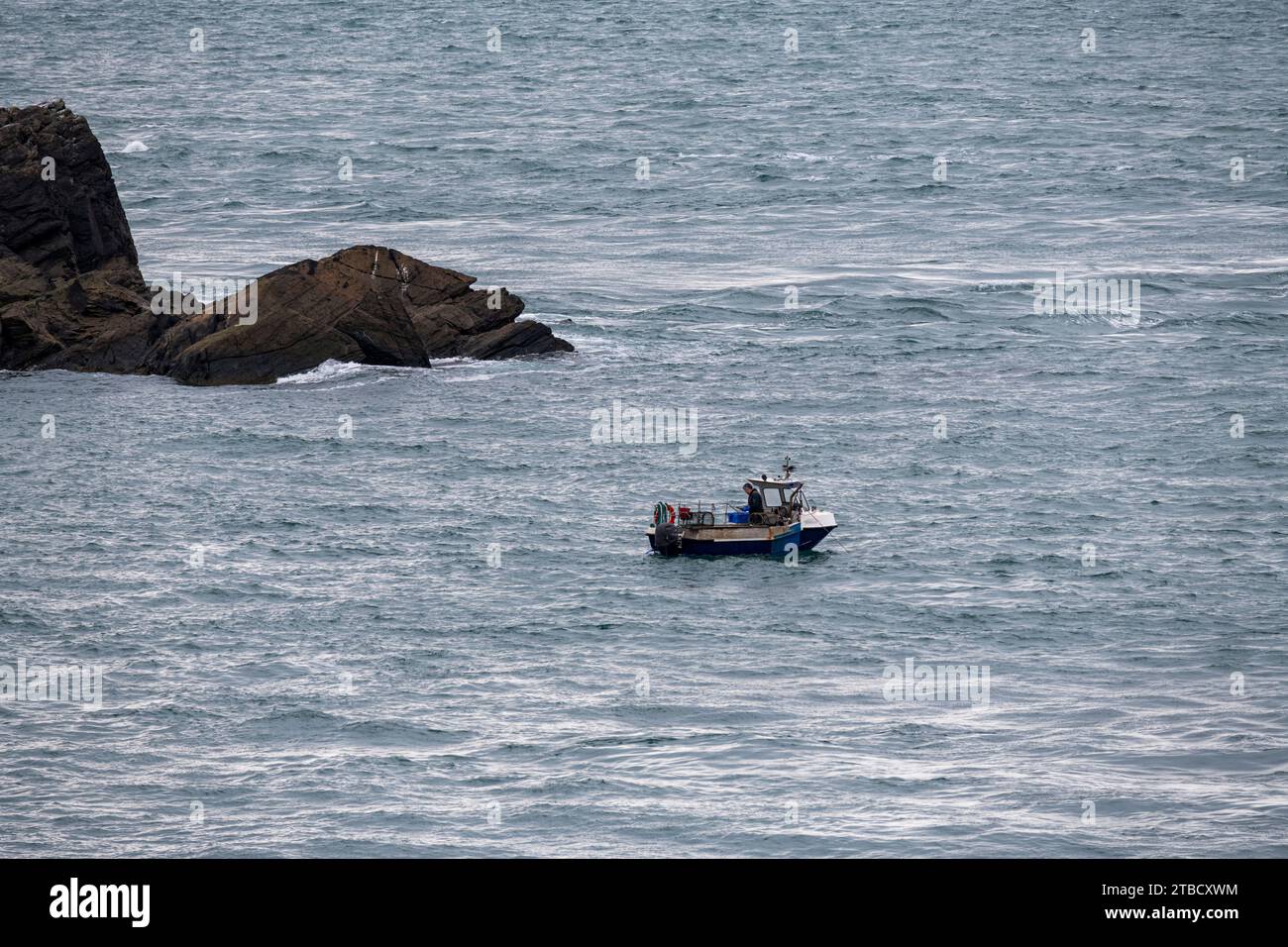 Kleines Fischerboot, das Hummertöpfe vor der Westküste von Anglesey, Nordwales, inspiziert. Stockfoto