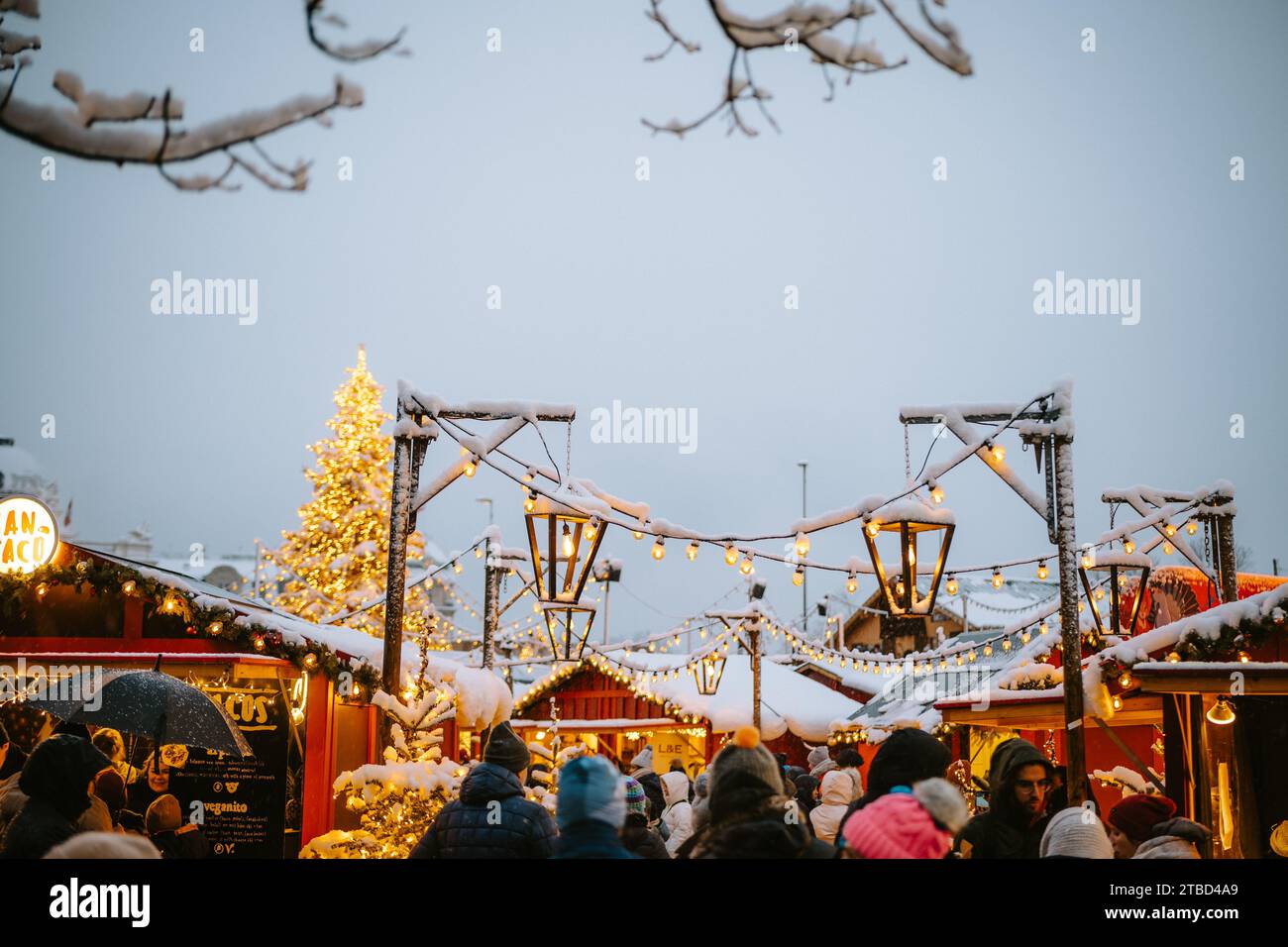 02.12.2023 Zürich, Schweiz. Leute, die Anfang Dezember bei Schneefall einen Weihnachtsmarkt besuchen. Spätabendliches Licht, Weihnachtsdekoration. Stockfoto