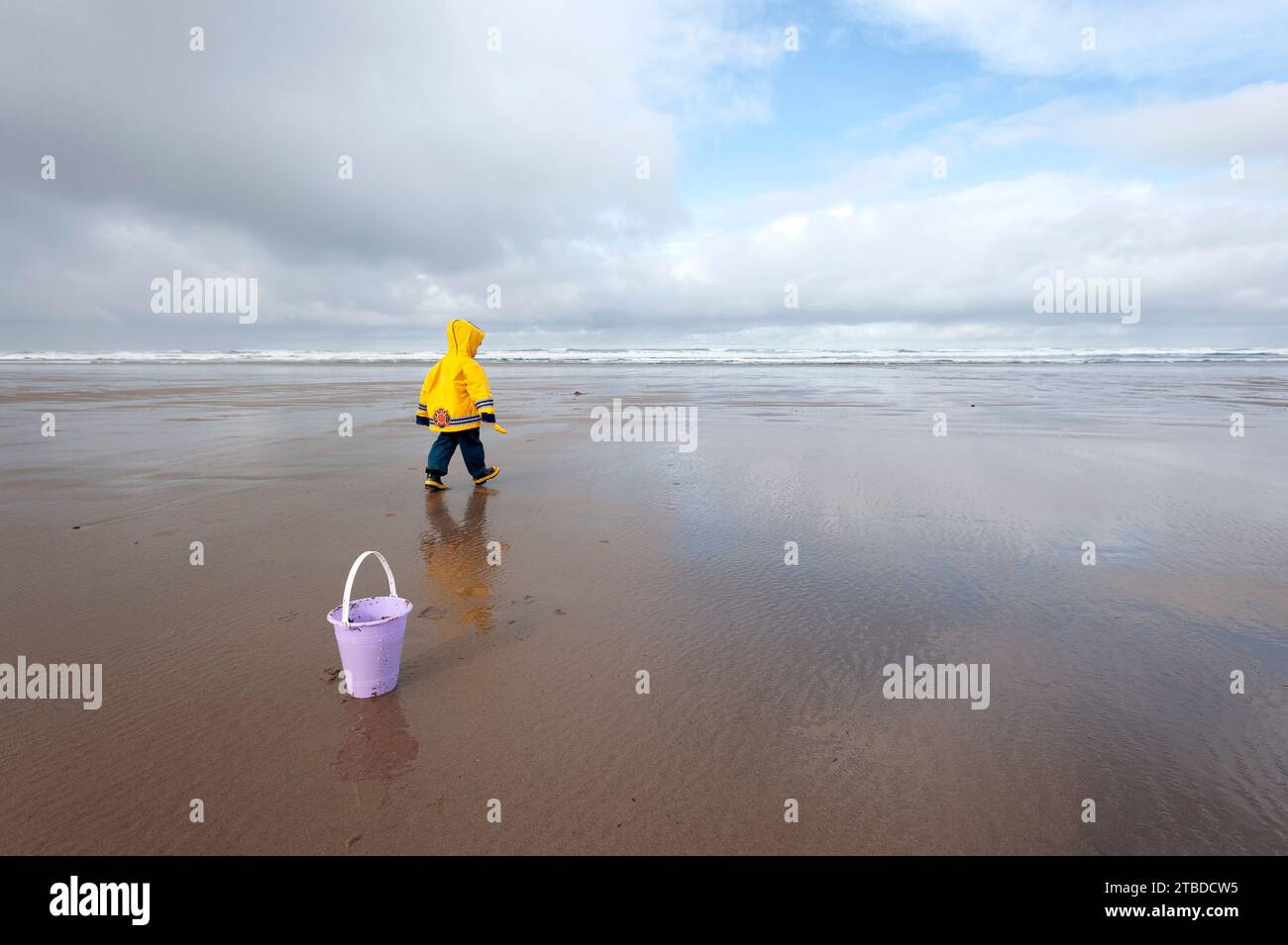 Einsames Kind, das am leeren Strand spaziert. Stockfoto