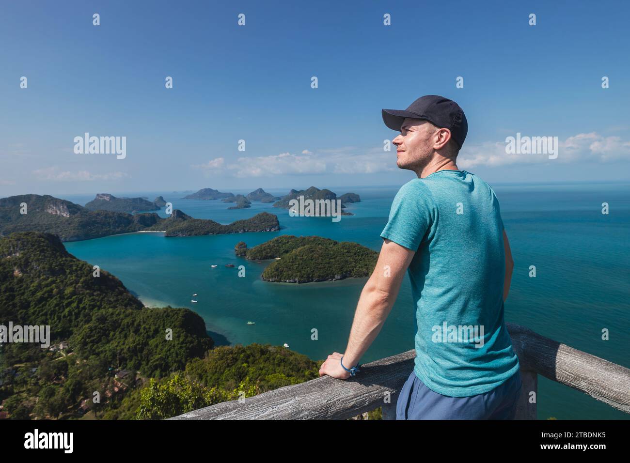 Glücklicher Mann genießt eine fantastische Aussicht vom Gipfel des Hügels. Gruppe tropischer Inseln im Meer in der Nähe von Koh Samui in Thailand. Stockfoto
