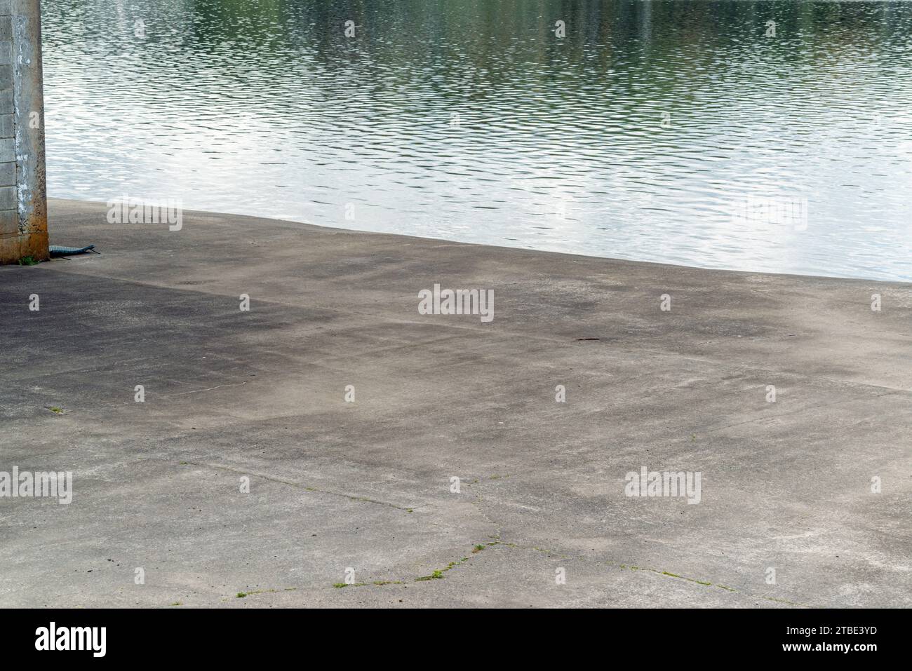 Fahrzeugrückwand oder Hintergrund mit einem Küstenparkplatz aus Beton oder Asphalt mit reflektierendem Meer dahinter. Stockfoto