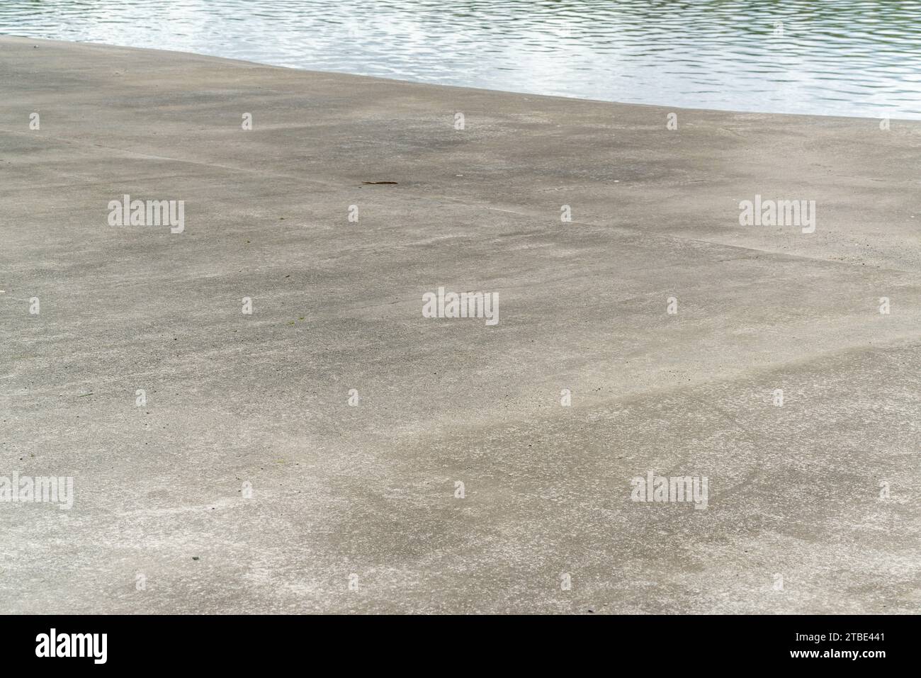 Fahrzeugrückwand oder Hintergrund mit einem Küstenparkplatz aus Beton oder Asphalt mit reflektierendem Meer dahinter. Stockfoto