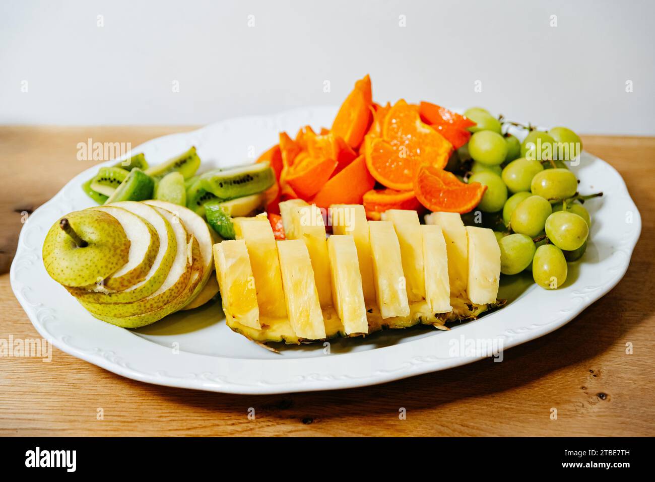 Verschiedene frische Fruchtscheiben, die ordentlich auf einer weißen Platte präsentiert werden, ideal für einen gesunden Snack oder ein Dessert. Stockfoto
