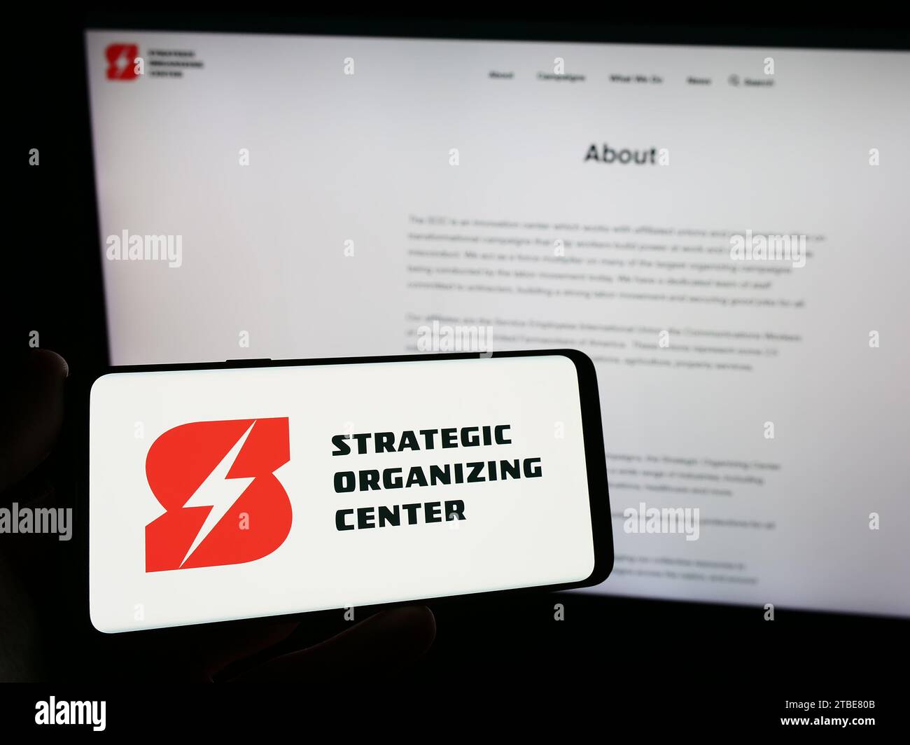 Person mit Smartphone und Logo des Strategic Organizing Center (SOC) der gewerkschaftskoalition vor der Website. Schwerpunkt auf dem Display des Telefons. Stockfoto