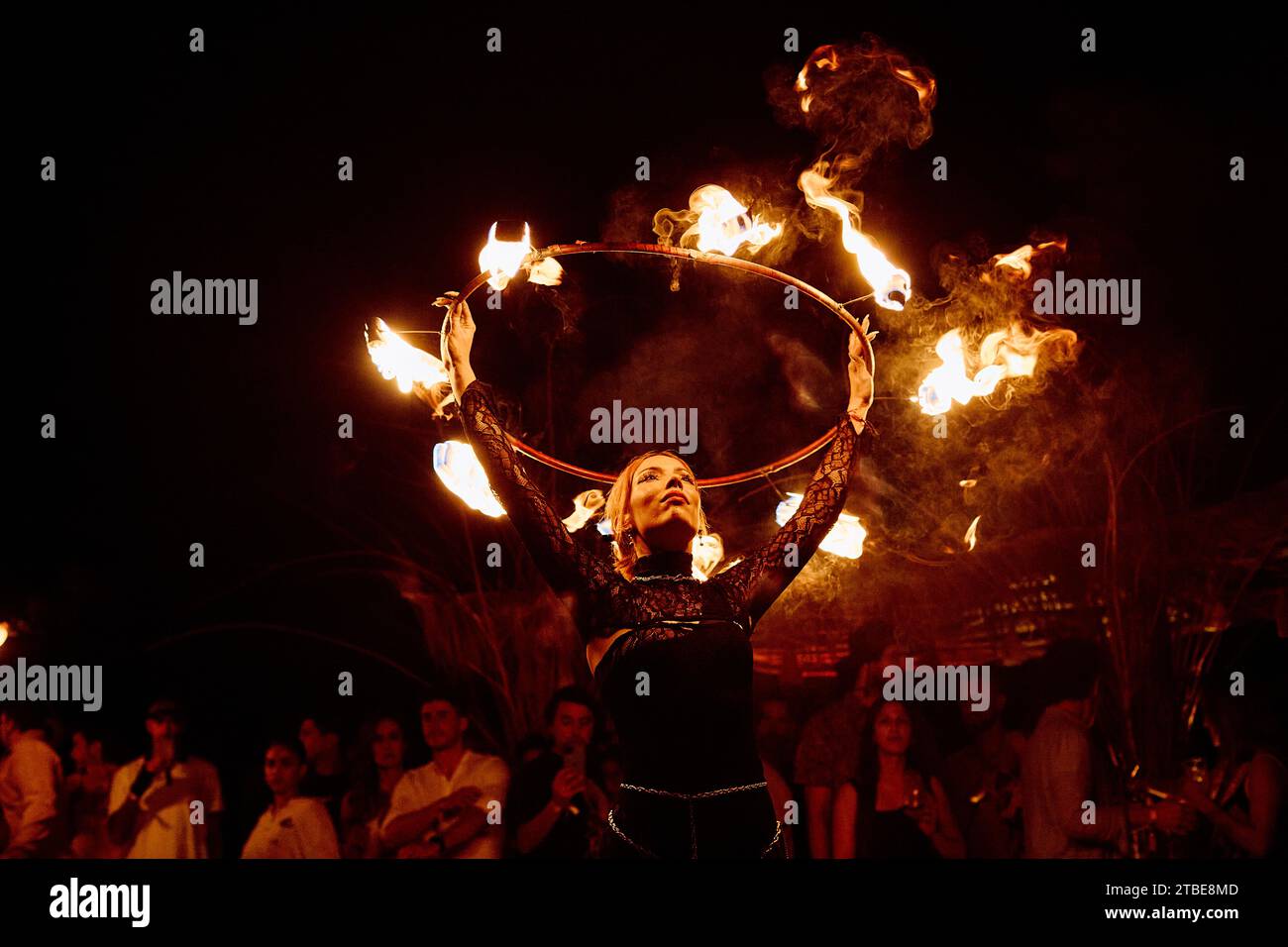 Künstler führen eine Feueraufführung vor, in der dunklen Nacht und vor einem Publikum, das aufmerksam zusieht. Stockfoto