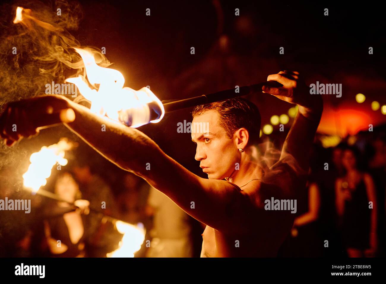 Künstler führen eine Feueraufführung vor, in der dunklen Nacht und vor einem Publikum, das aufmerksam zusieht. Stockfoto