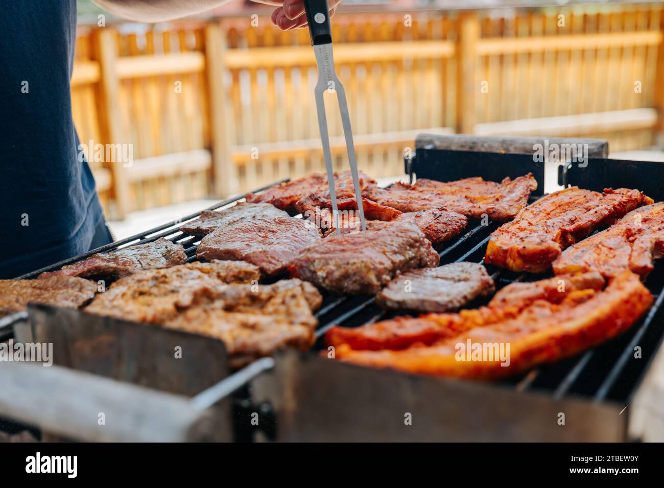 BBQ Picknick draußen. Gegrillter Schweinebauch in Marinade. Fleisch dreht sich auf dem Grill. Appetitliches gebratenes Schweinefleisch. BBQ und Grill. Gegrilltes Fleisch. Picknick im Freien Stockfoto