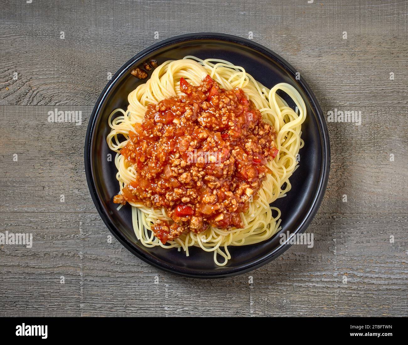 Teller mit Pasta-Spaghetti mit Bolognese-Sauce auf hölzernem Küchentisch, Blick von oben Stockfoto