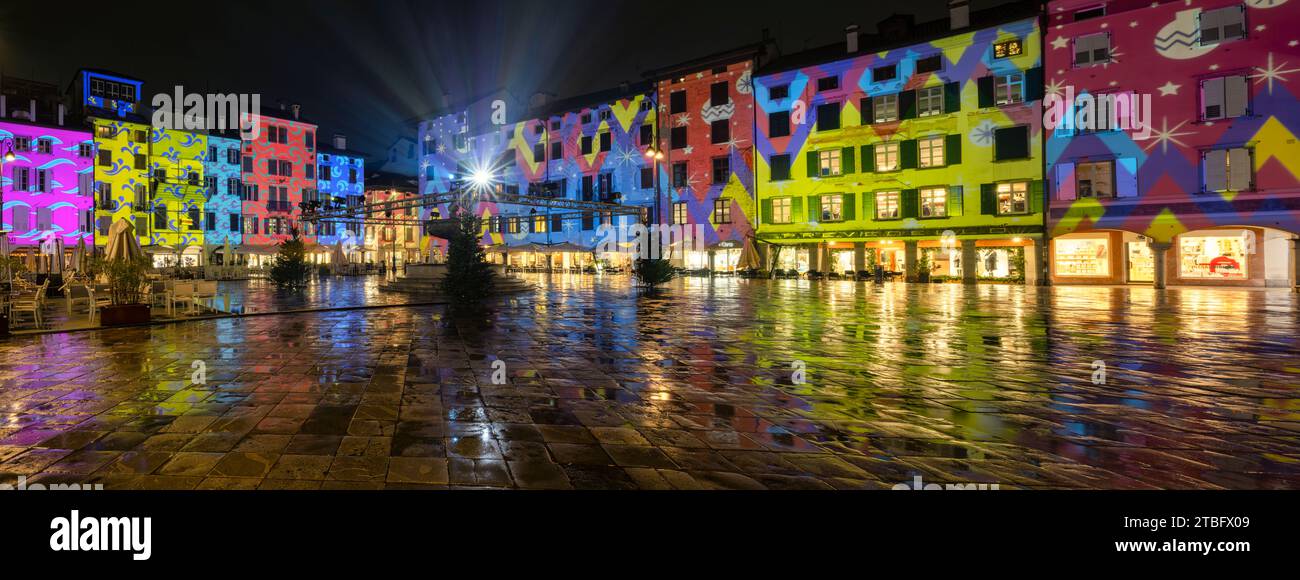 Weihnachtsdekoration und Beleuchtung auf einem italienischen Platz. Häuser der piazza San Giacomo mit bunten Lichtern bemalt. Udine, Friaul-Julisch Venetien. Stockfoto