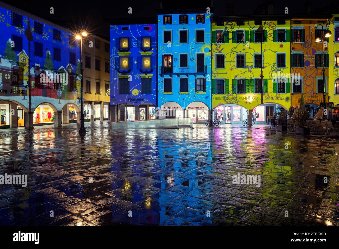 Weihnachtsdekoration und Beleuchtung auf einem italienischen Platz. Häuser der piazza San Giacomo mit bunten Lichtern bemalt. Udine, Friaul-Julisch Venetien. Stockfoto