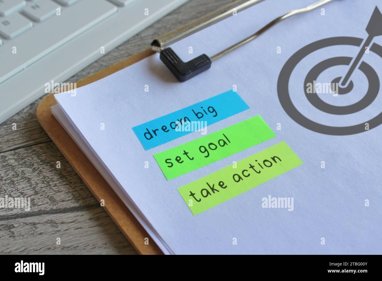 Nahaufnahme der Zwischenablage aus Papier mit dem Symbol für die Zieltafel und Text TRÄUMEN SIE GROSS, SETZEN SIE SICH EIN ZIEL und ERGREIFEN SIE MASSNAHMEN. Motivationskonzept. Stockfoto