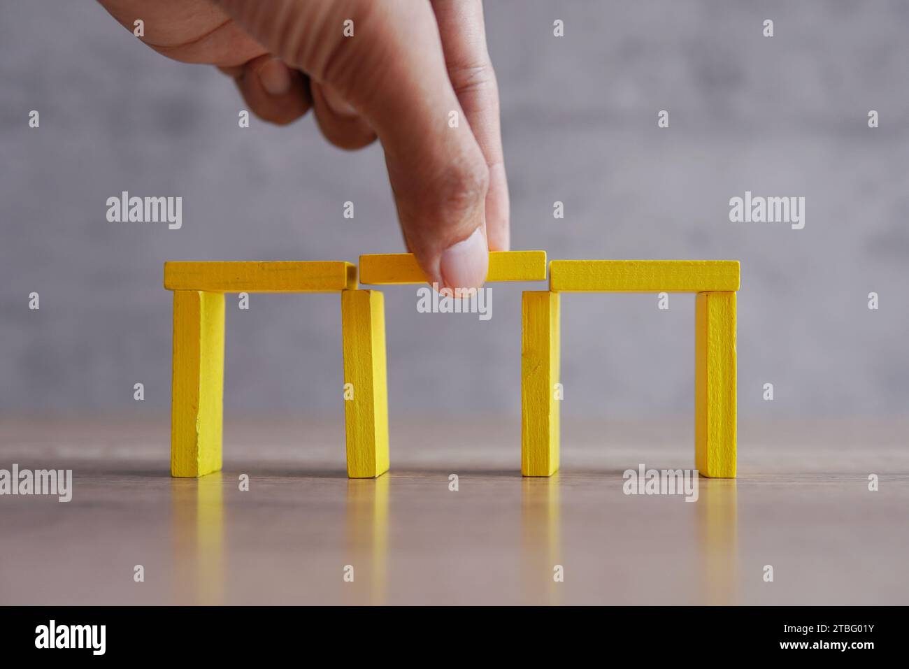 Fügen Sie Holzblöcke von Hand zwischen die Lücke, um die Brücke zu vervollständigen. Lösung: Das Konzept der Lücke füllen. Stockfoto