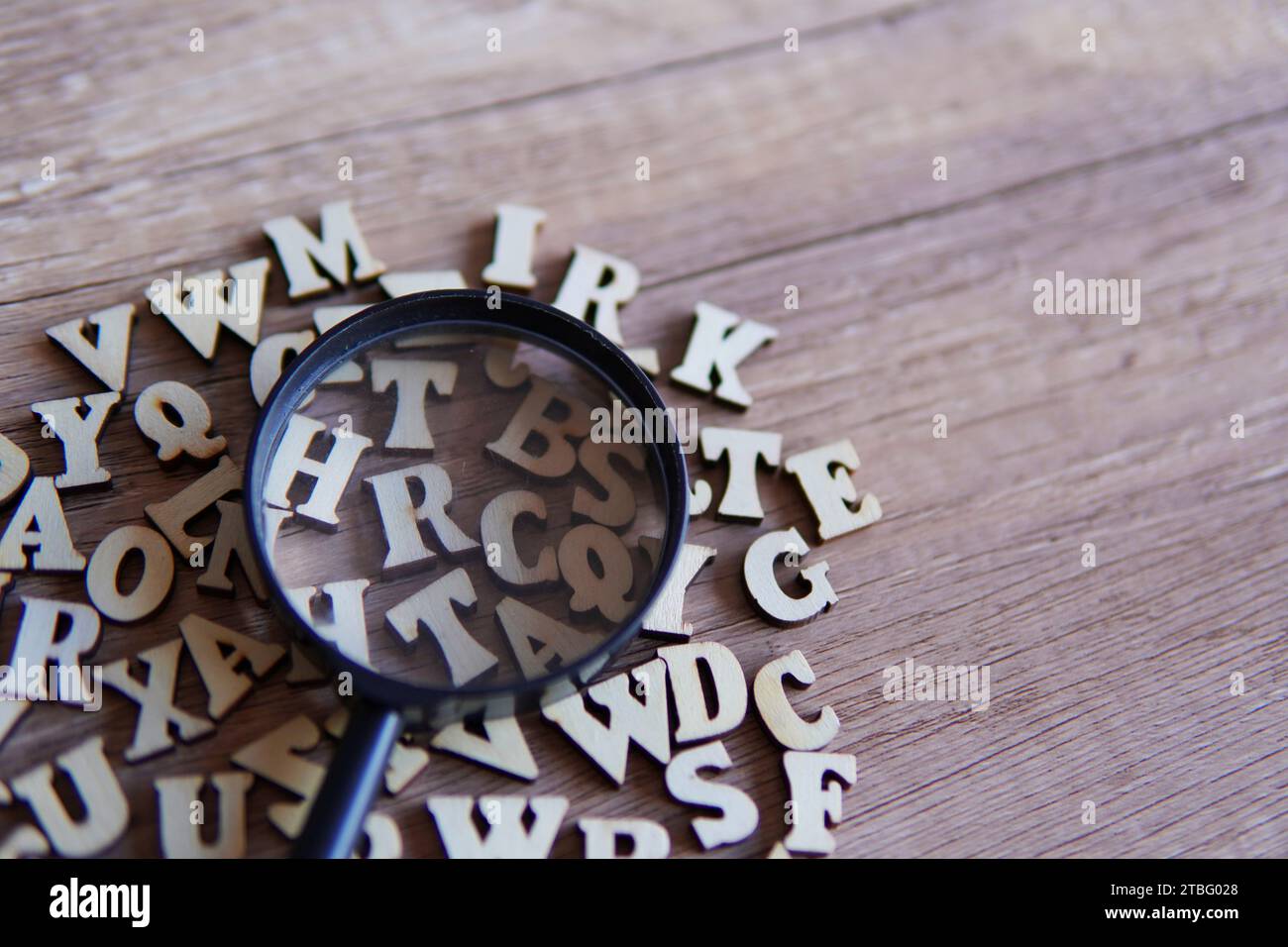 Lupe mit verstreuten Buchstaben auf dem Tisch. Kopierbereich für Text. Bildungskonzept. Stockfoto