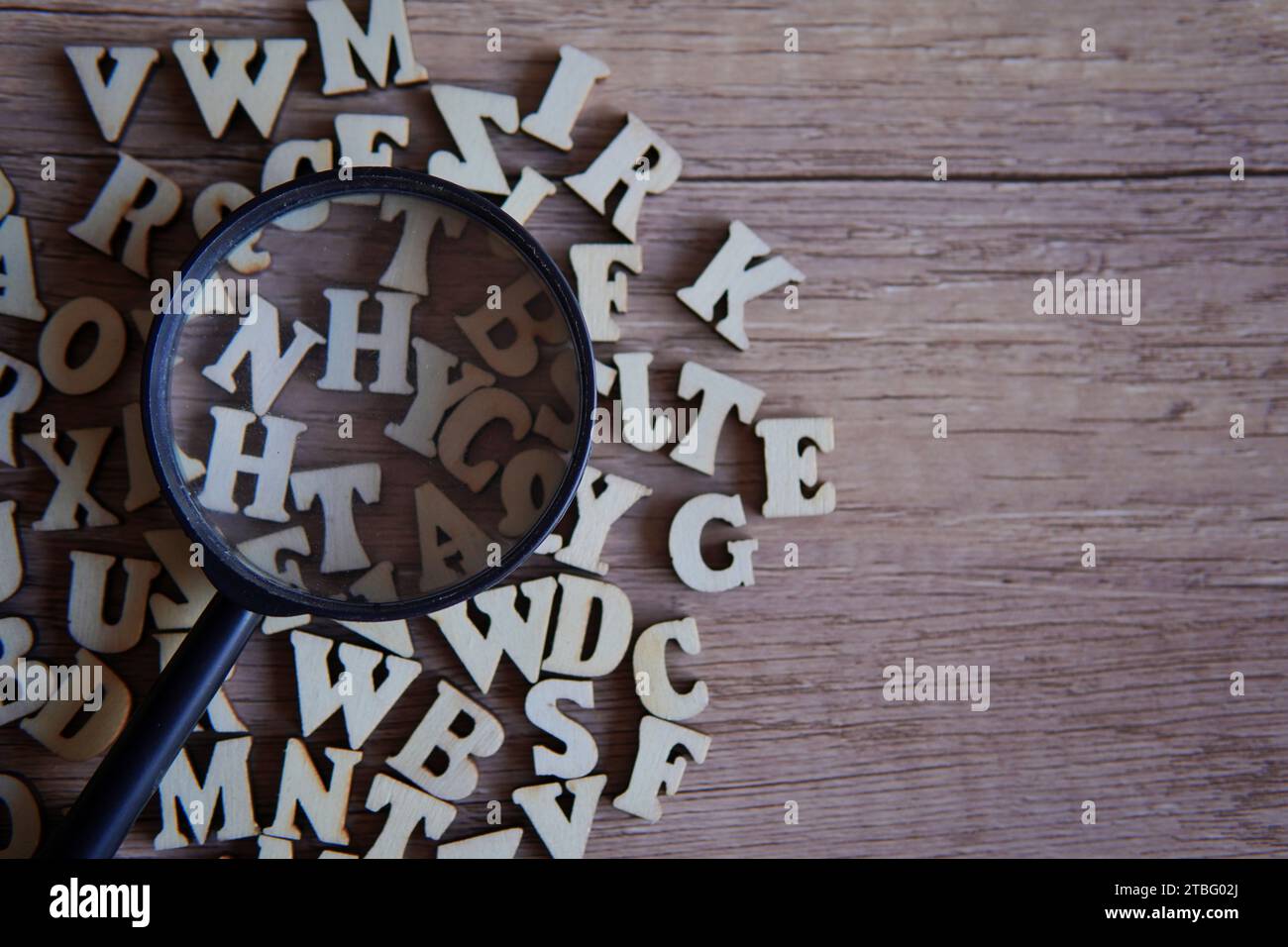 Lupe mit verstreuten Buchstaben auf dem Tisch. Kopierbereich für Text. Bildungskonzept. Stockfoto