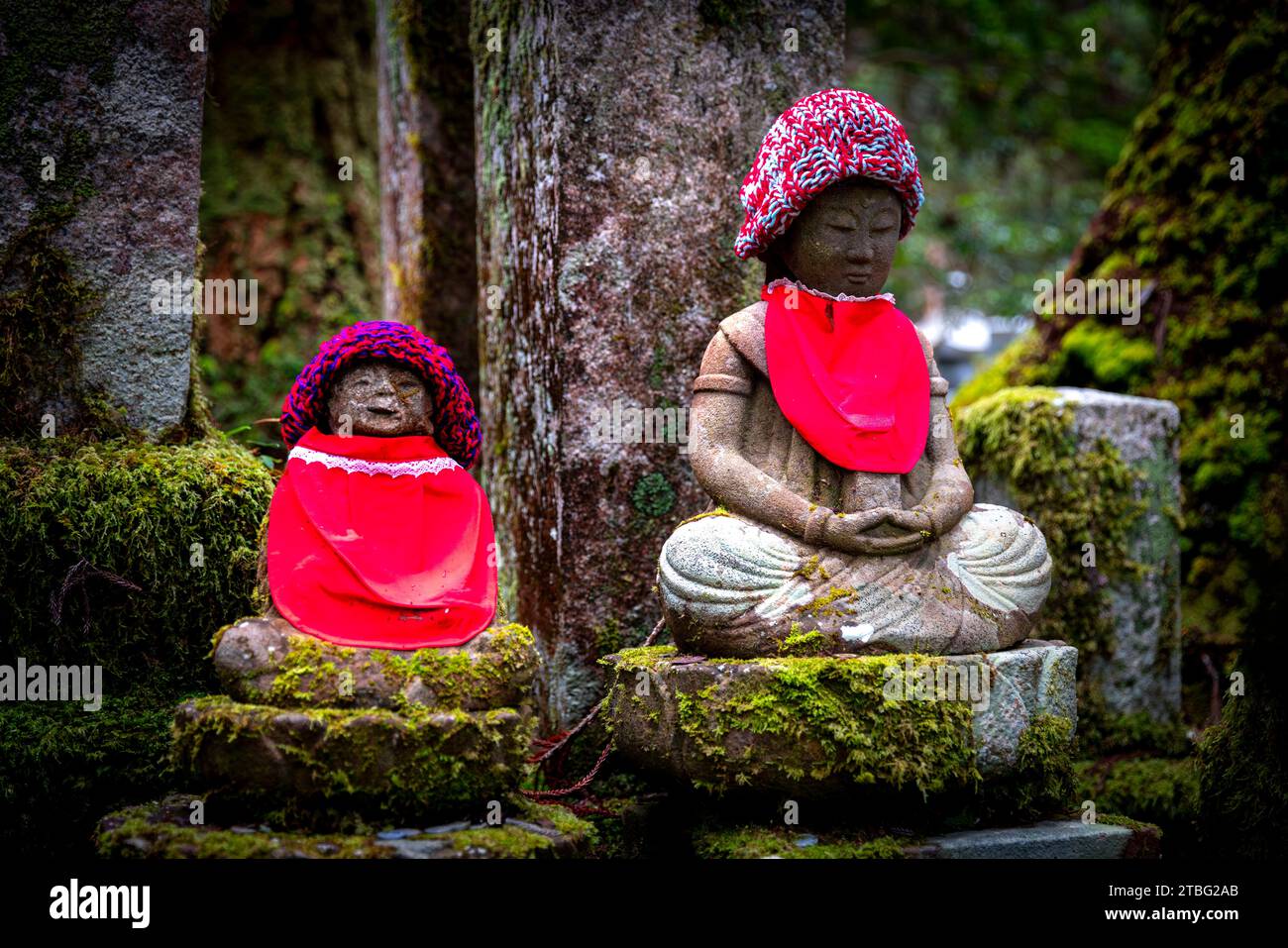 Grabstatuen mit roten Verzierungen auf dem Okunoin Friedhof auf dem Berg koya Stockfoto