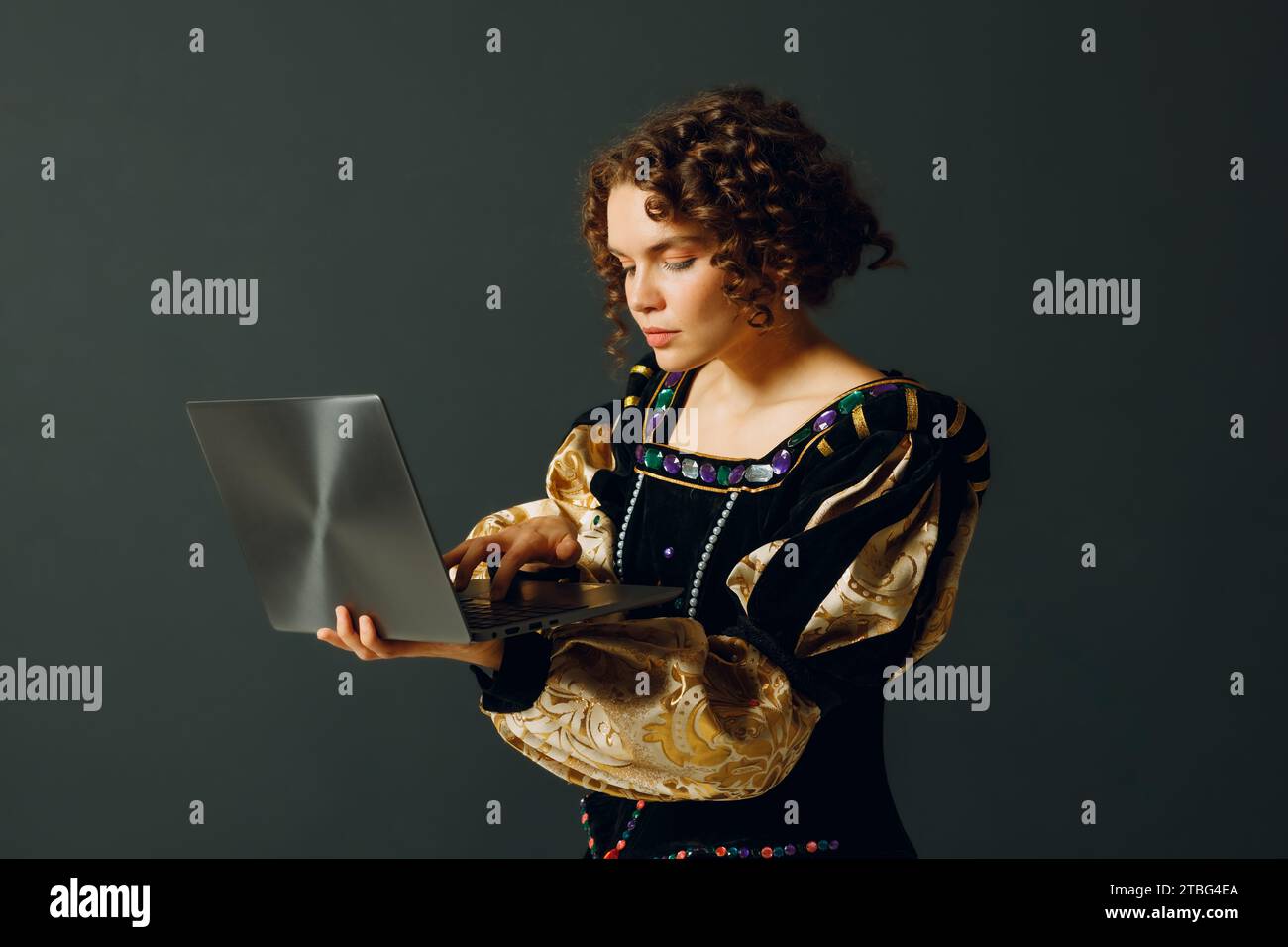 Porträt einer jungen Aristokratin in einem mittelalterlichen Kleid, die am Laptop arbeitet Stockfoto