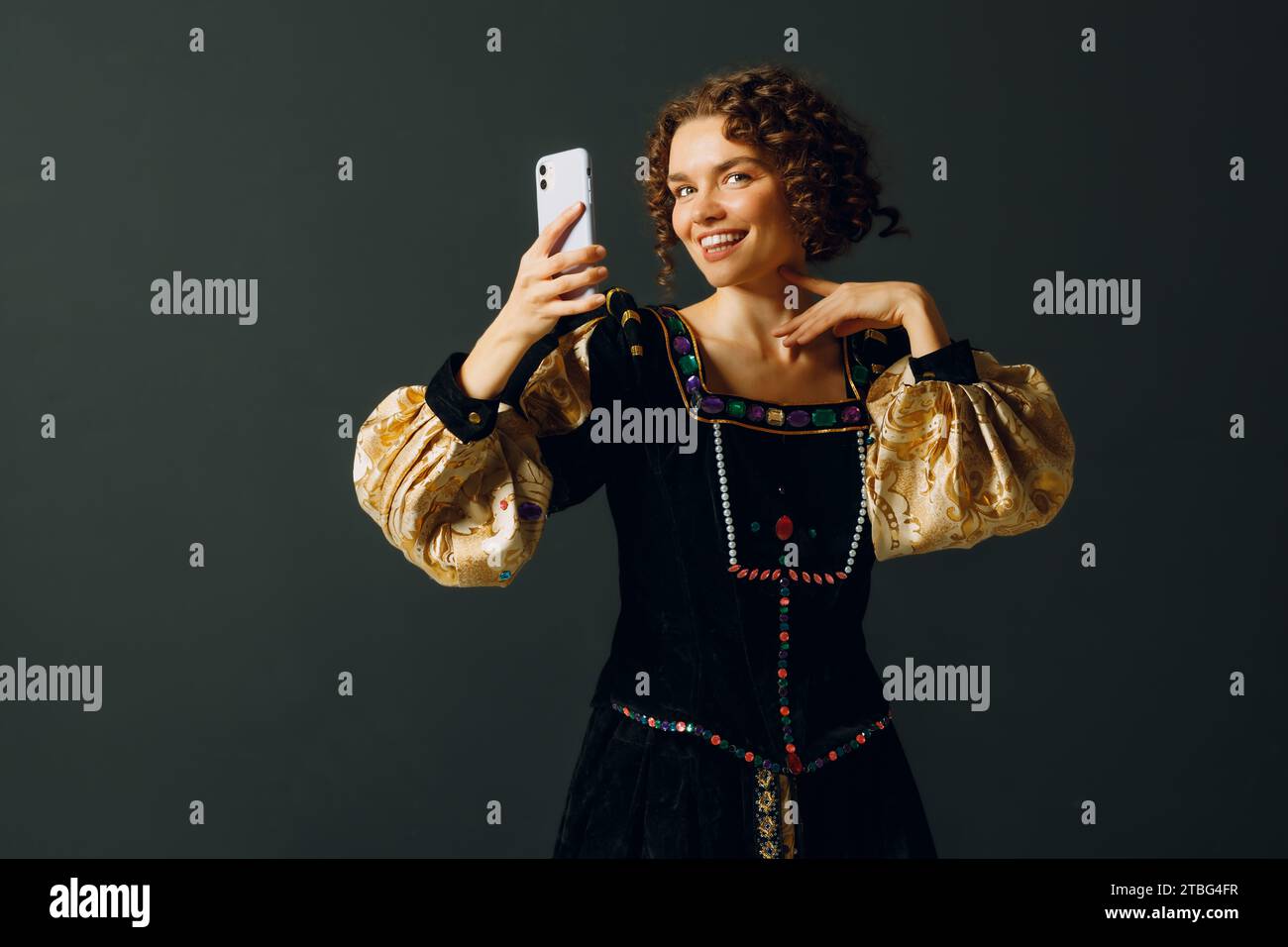 Porträt einer jungen Aristokratin, die ein Foto-Selfie mit Handy macht und in einem mittelalterlichen Kleid gekleidet ist Stockfoto