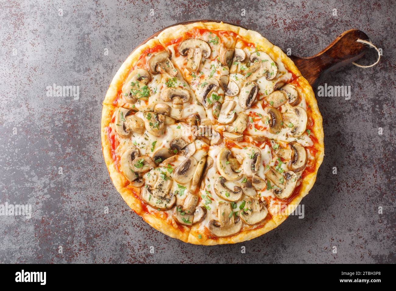 Vegetarische Pilzpizza mit portobello, Mozzarella, Knoblauch, Tomaten und Petersilie in Nahaufnahme auf einem Holzbrett auf dem Tisch. Horizontale Draufsicht von Stockfoto