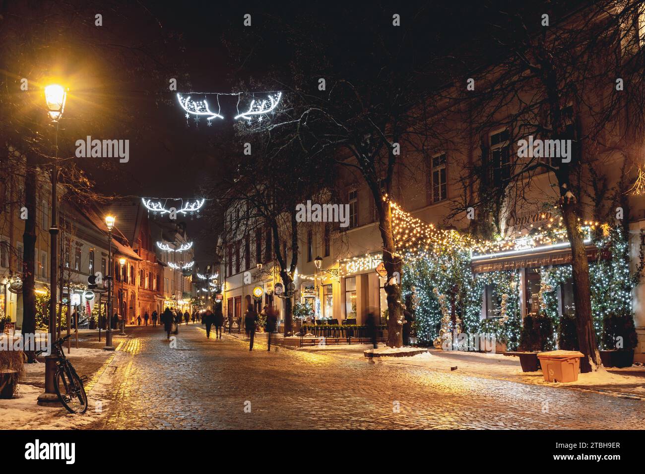 Wunderschöne gemütliche Weihnachtsdekoration, Kranz, Girlanden und Lichter in der Altstadt von Vilnius, Hauptstadt von Litauen, Europa, bei Nacht mit Straßenlaternen, Fahrrad Stockfoto