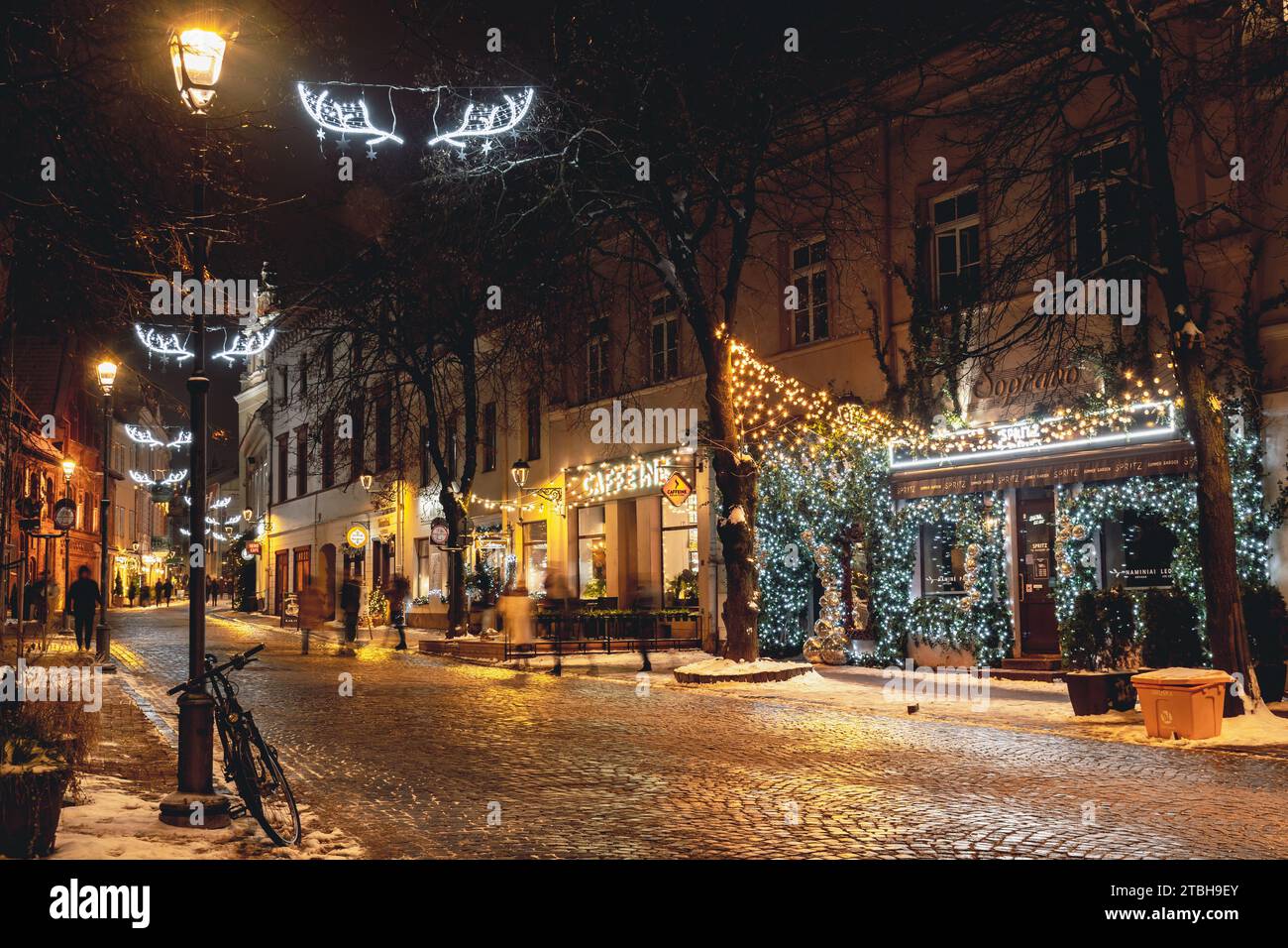 Wunderschöne gemütliche Weihnachtsdekoration, Kranz, Girlanden und Lichter in der Altstadt von Vilnius, Hauptstadt von Litauen, Europa, bei Nacht mit Straßenlaternen, Fahrrad Stockfoto