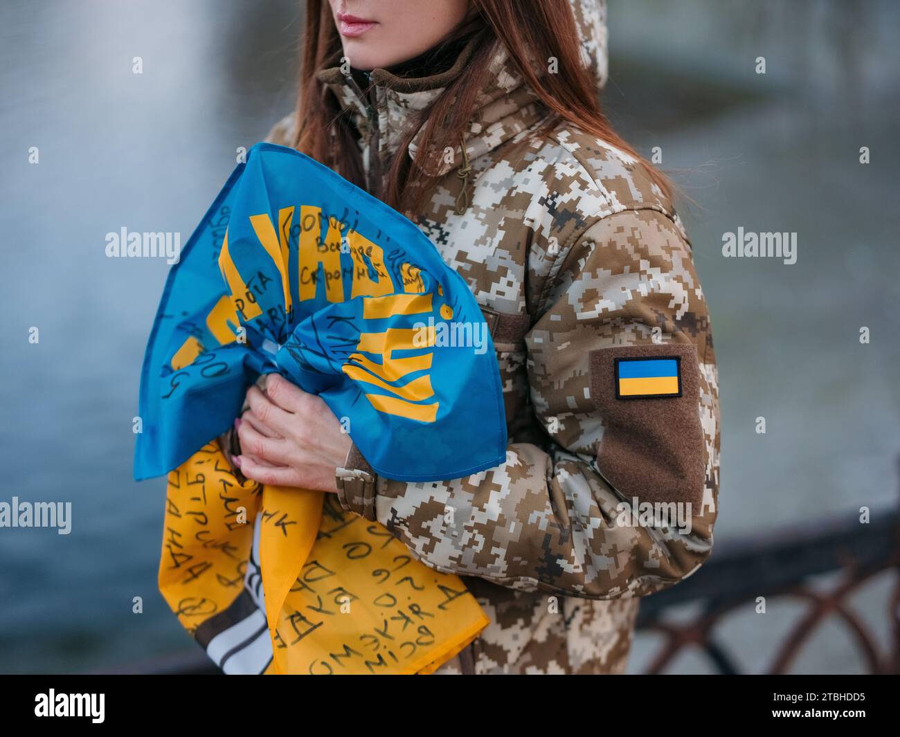 Ukrainische Soldatenfrau mit Flagge und Unterschriften ukrainischer Krieger und ruht im Park im Urlaub. Übersetzung aus dem Ukrainischen: Ruhm ins Ukrai Stockfoto