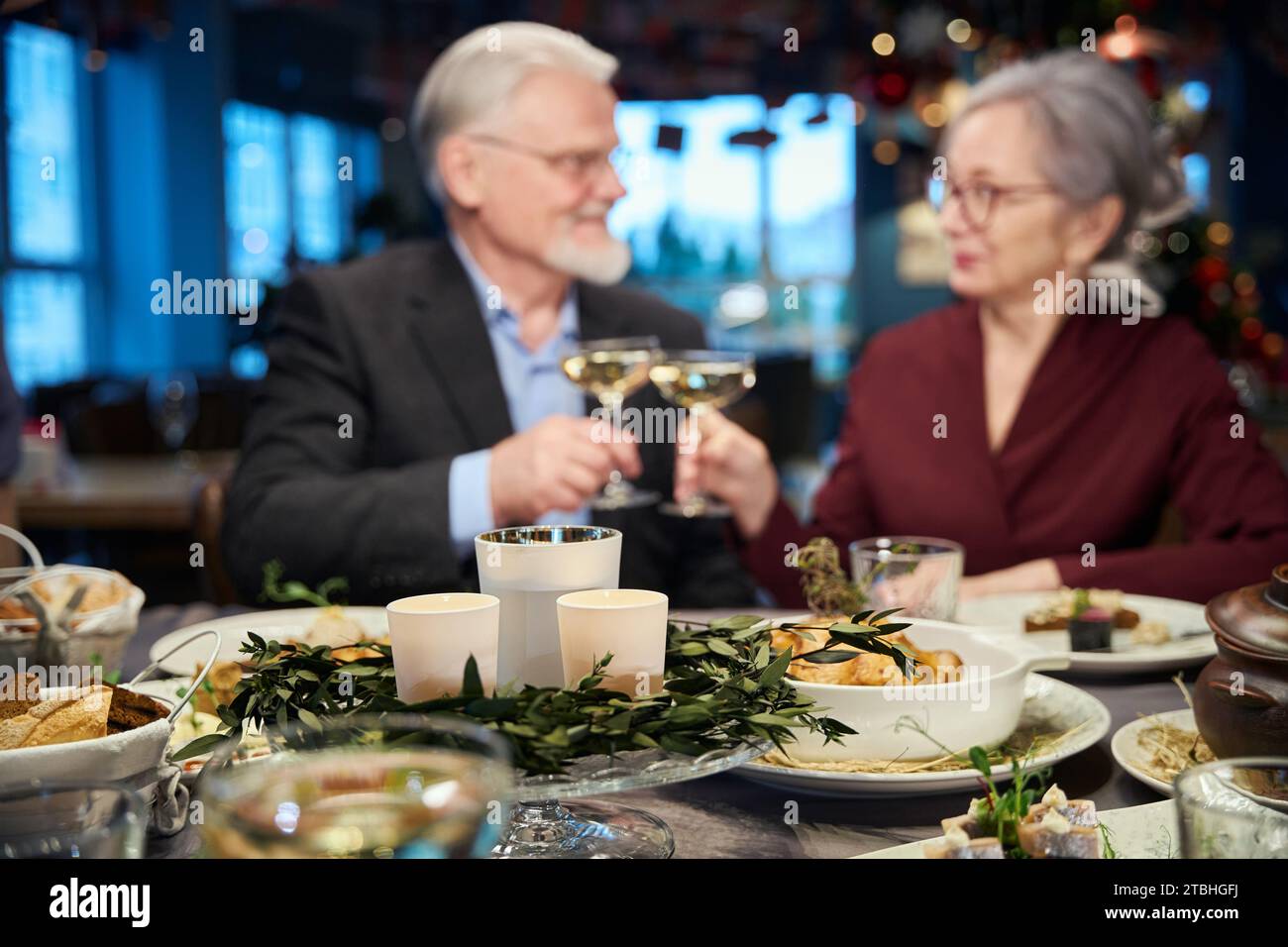 Älteres Ehepaar feiert Silvester zusammen und klirrt Gläser mit Champagner an Stockfoto